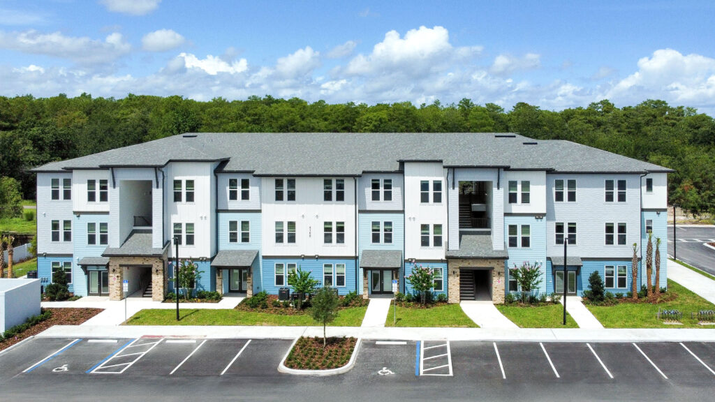 Pinnacle at The Wesleyan affordable apartment community exterior in Kissimmee Florida showing three-story residential buildings with modern architecture and parking
